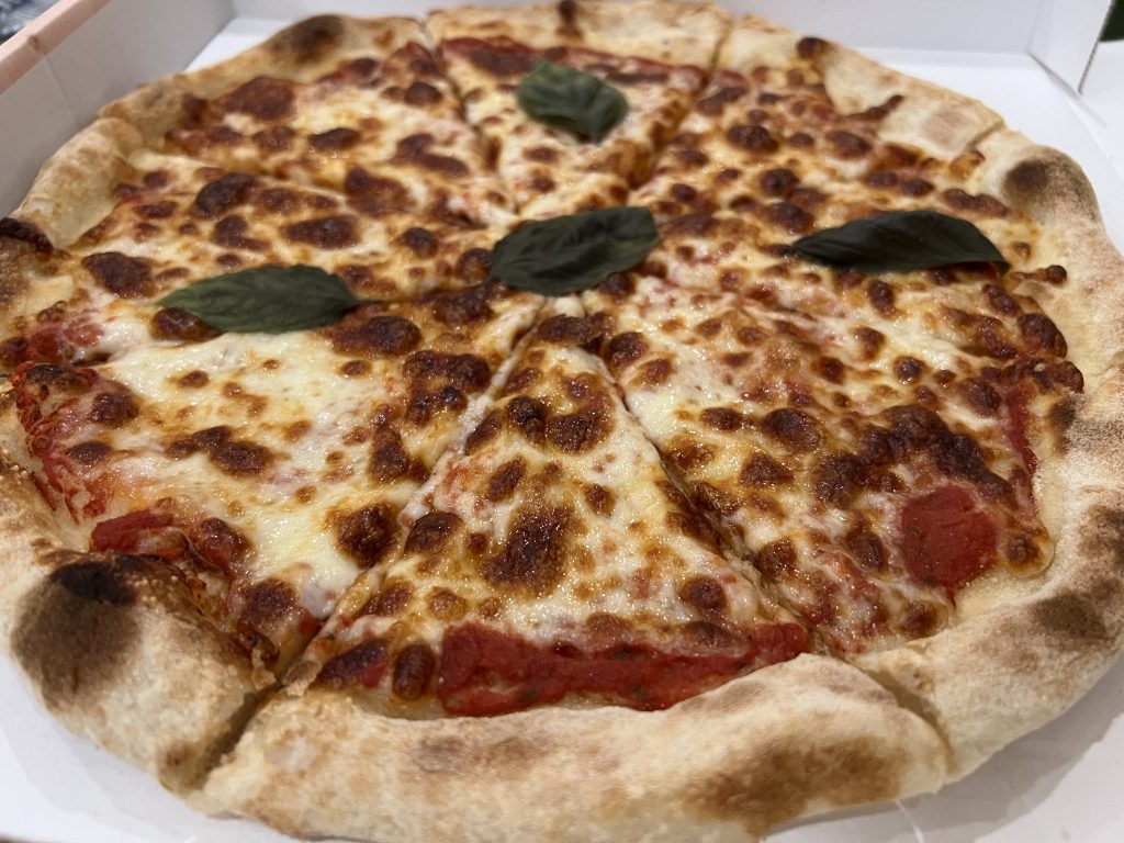 Cheesy pizza with fresh basil leaves at Sapori da Giovanni