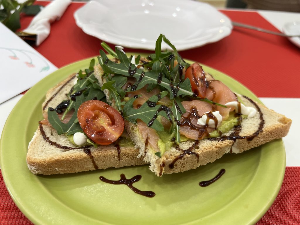 A close up of Avocado smoked salmon and arugula toast on a green plate at MB Cakes Brunch & Coffee Photos & Review