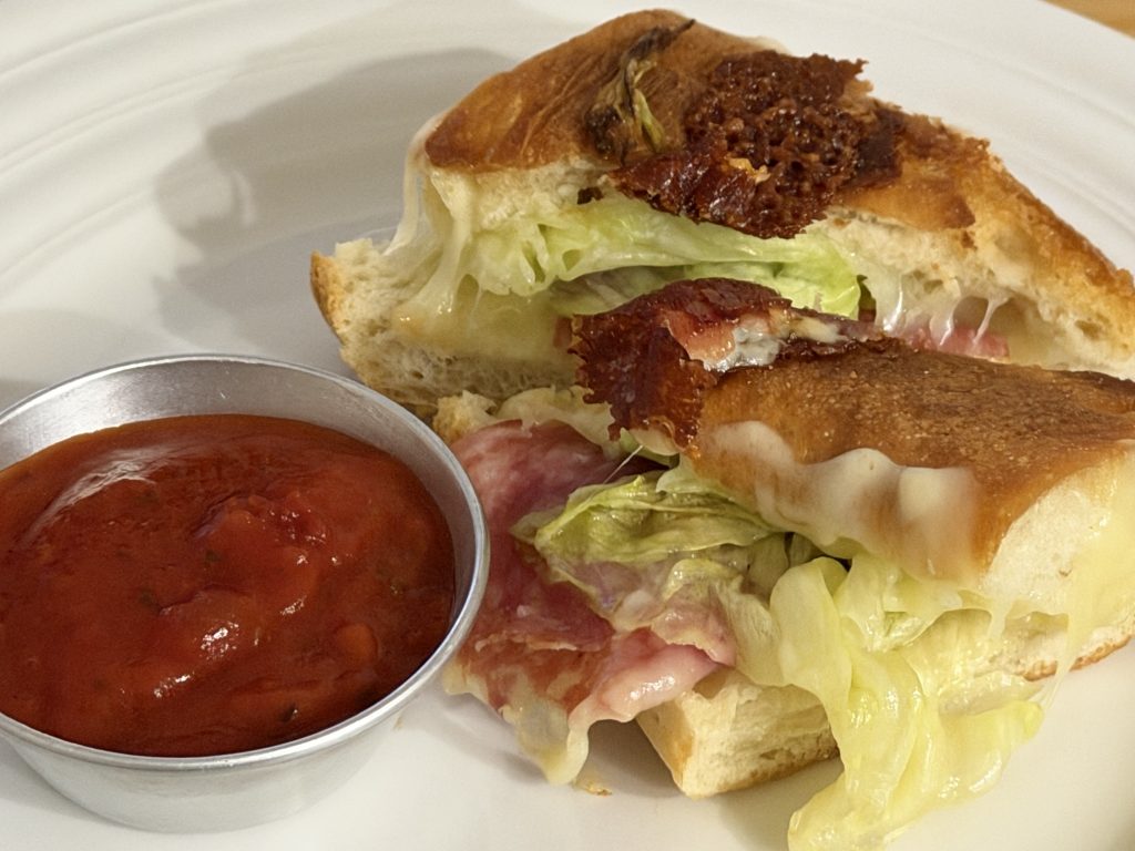 Cucina Arrabbiata Sauce Review — Cup of Sauce beside Toasted Salame Cheese and Lettuce Sandwich on a White Ceramic Plate | Aldi Finds Portugal 