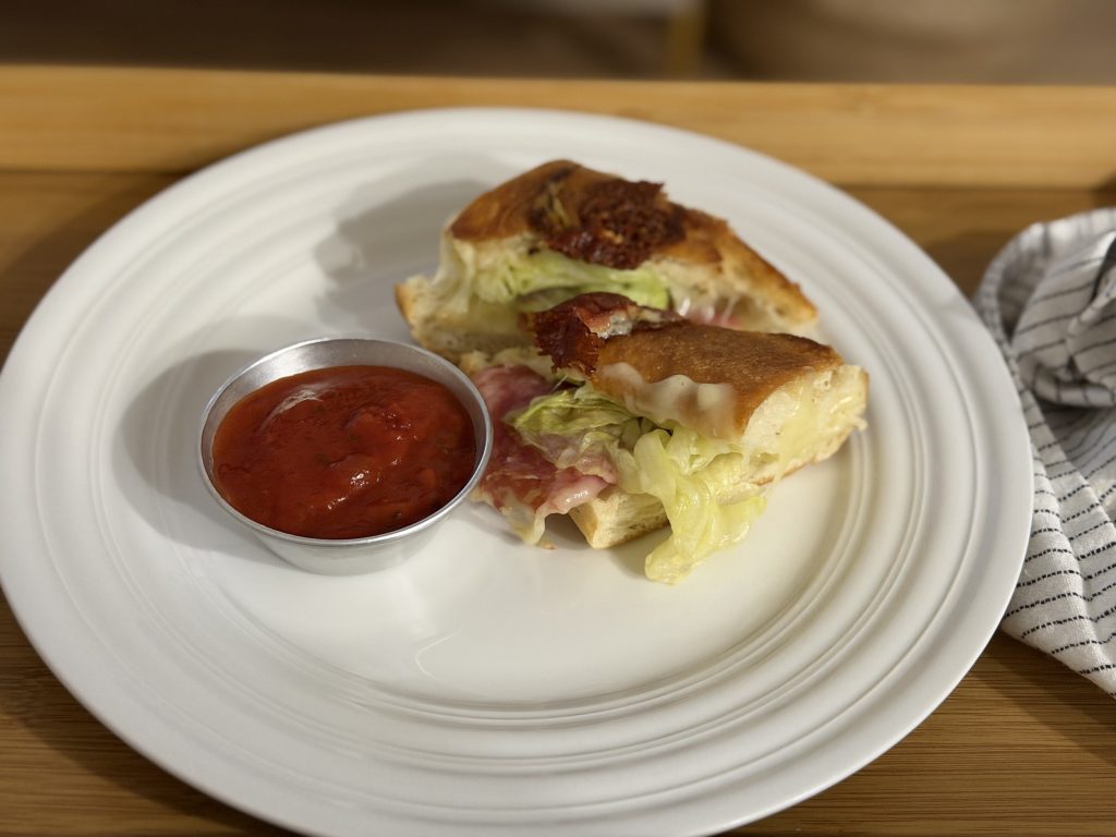 Cucina Arrabbiata Sauce Review — Serving Suggestion: Toasted Italian Sandwich on a Plate with a Cup of Warm sauce | Aldi Finds Portugal 
